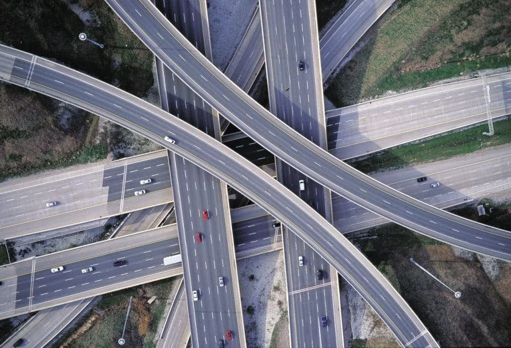 An aerial view of multiple overlapping highway overpasses with several cars driving on them.