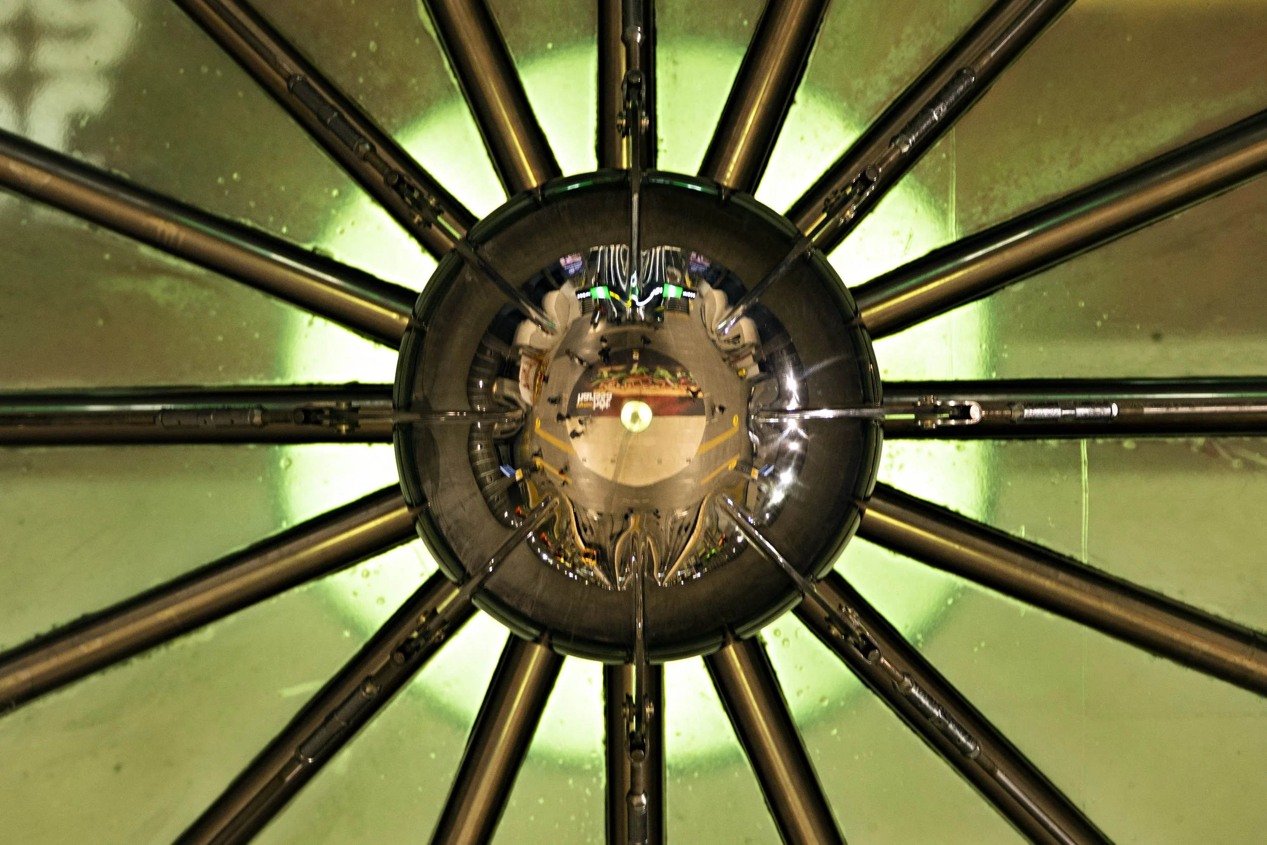 A view from the bottom of the Large Hadron Collider, looking up at the circular structure with multiple metallic pipes extending outward in a radial pattern.