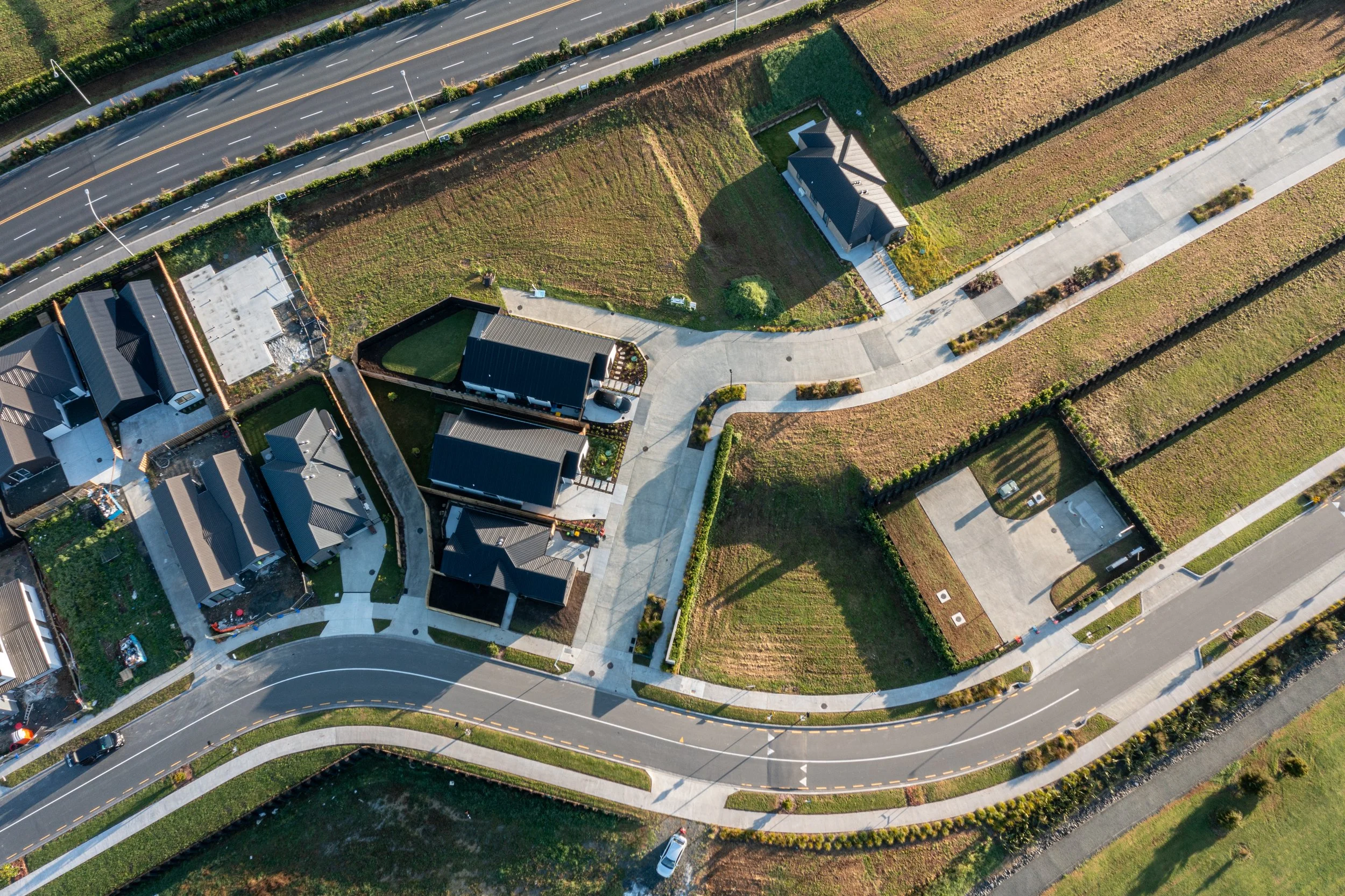 Aerial view of a suburban area showing residential homes, roads, and landscaped yards with fencing and greenery.
