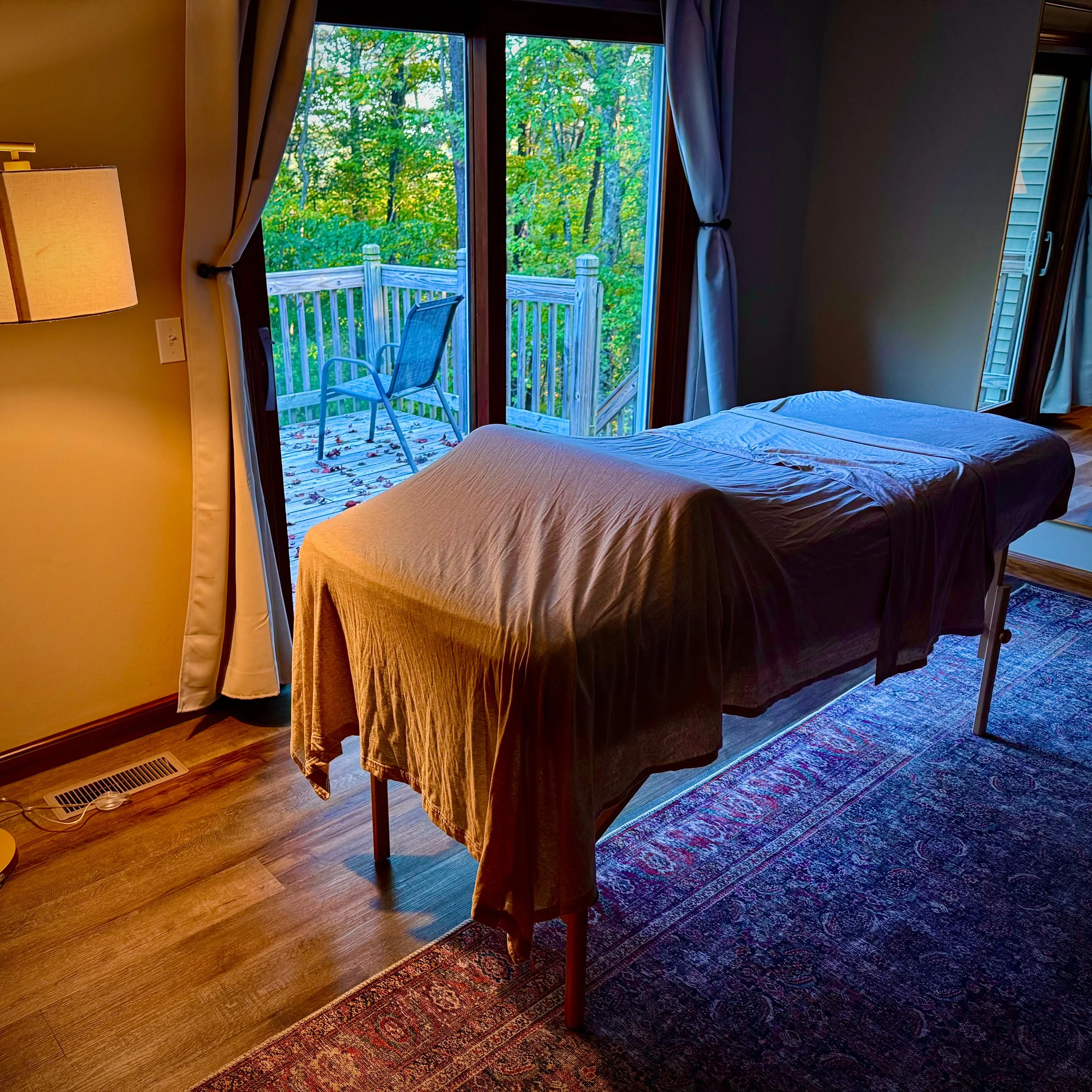 Massage table set up in cozy room next to window looking out in to nature