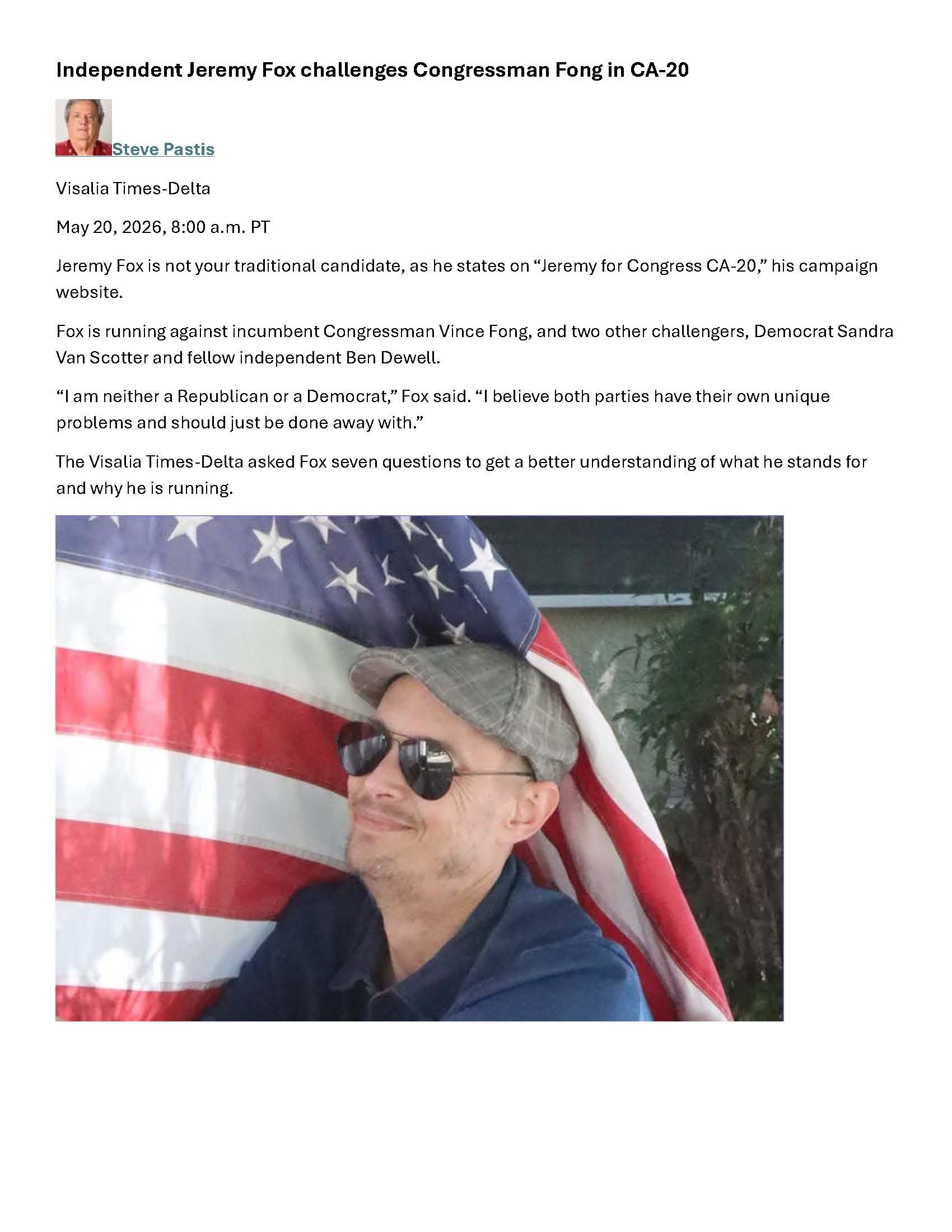 Jeremy Fox in a wheelchair partially hidden by a waving American flag, wearing sunglasses and a flatcap.