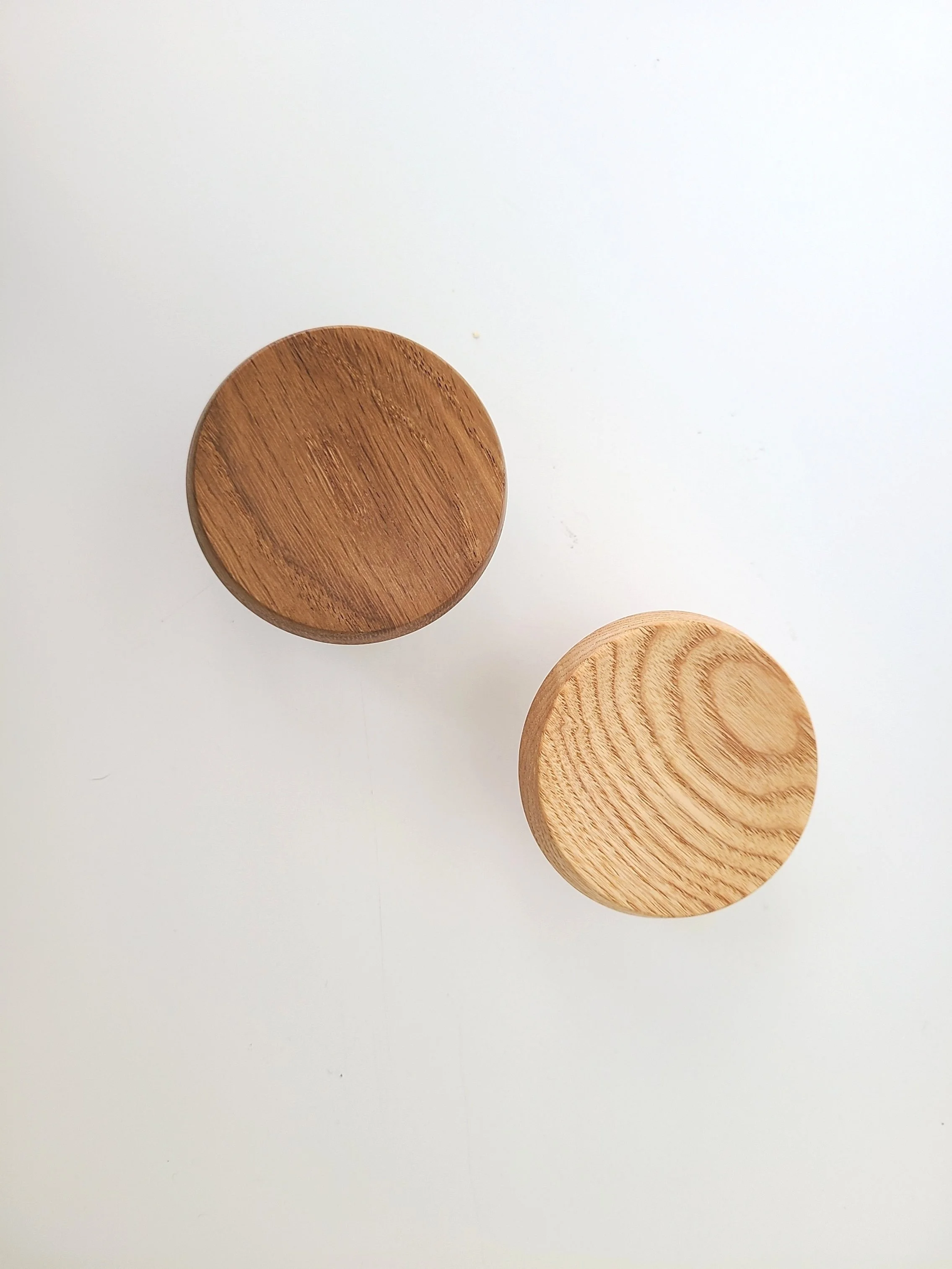 Top view of two round wooden objects, one dark and one light, placed on a white surface.