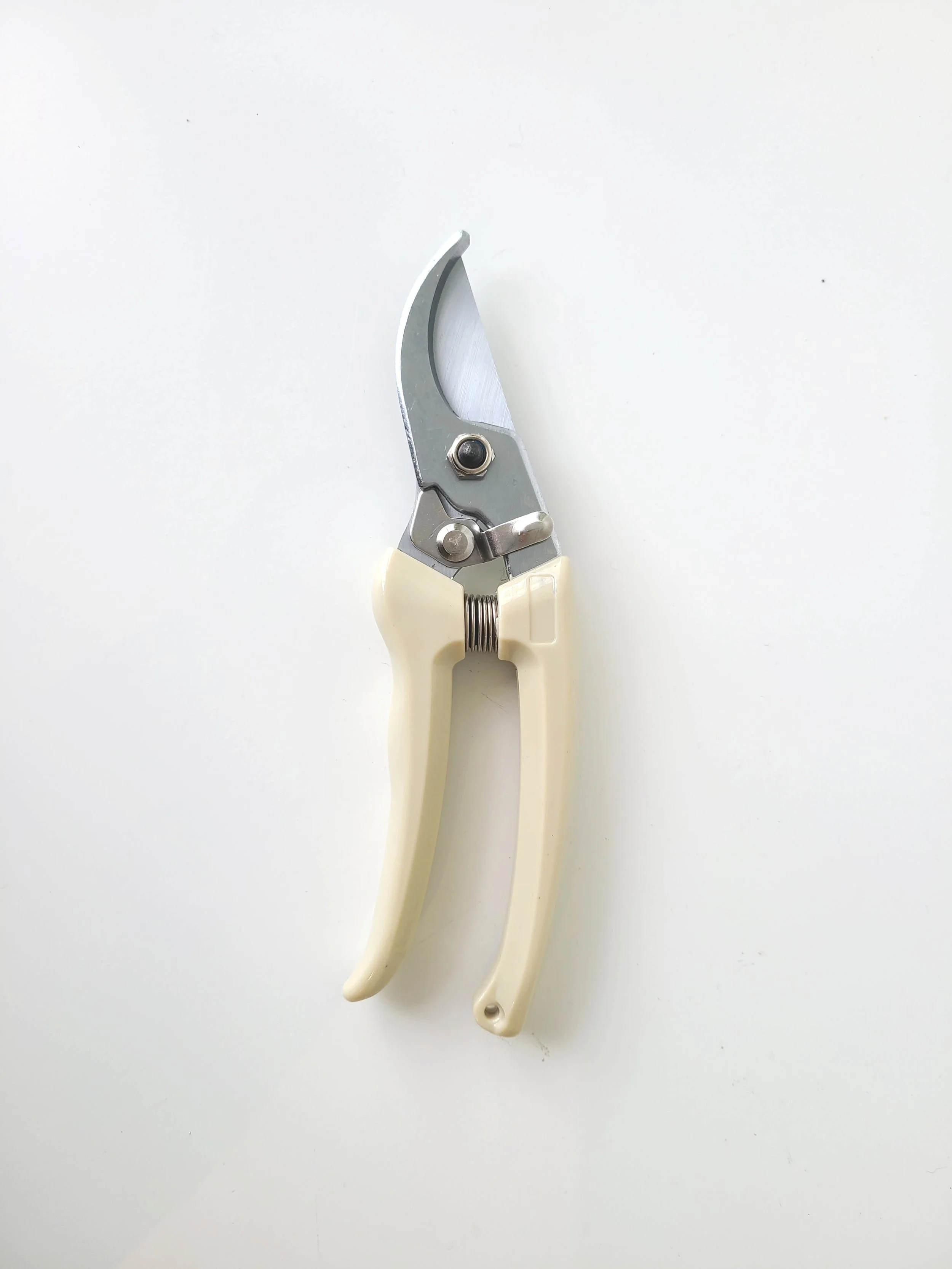 A pair of pruning shears with cream-colored handles on a white surface.