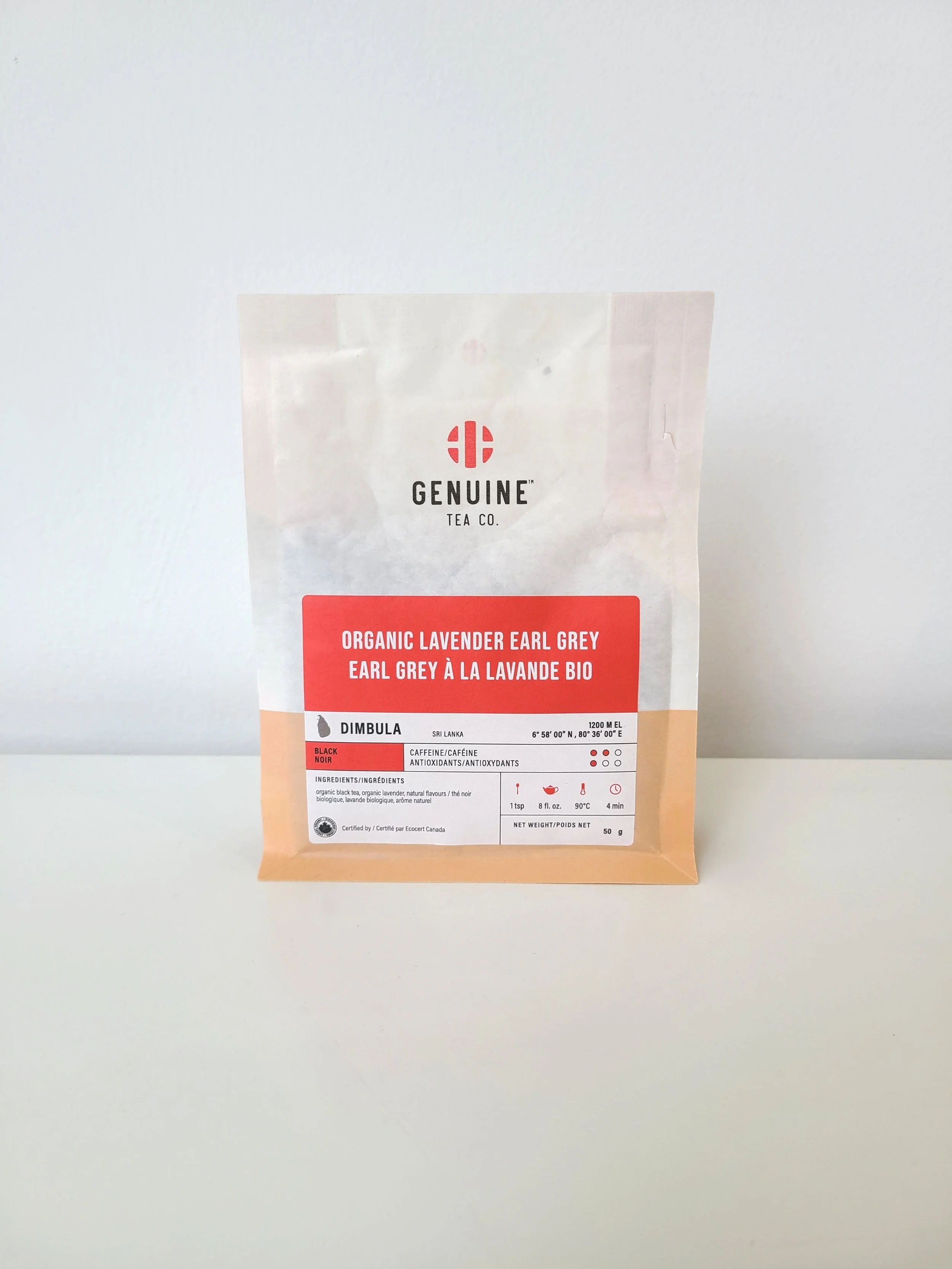 A package of organic lavender Earl Grey tea from GENUINE TEA CO. sitting on a white surface against a white wall.