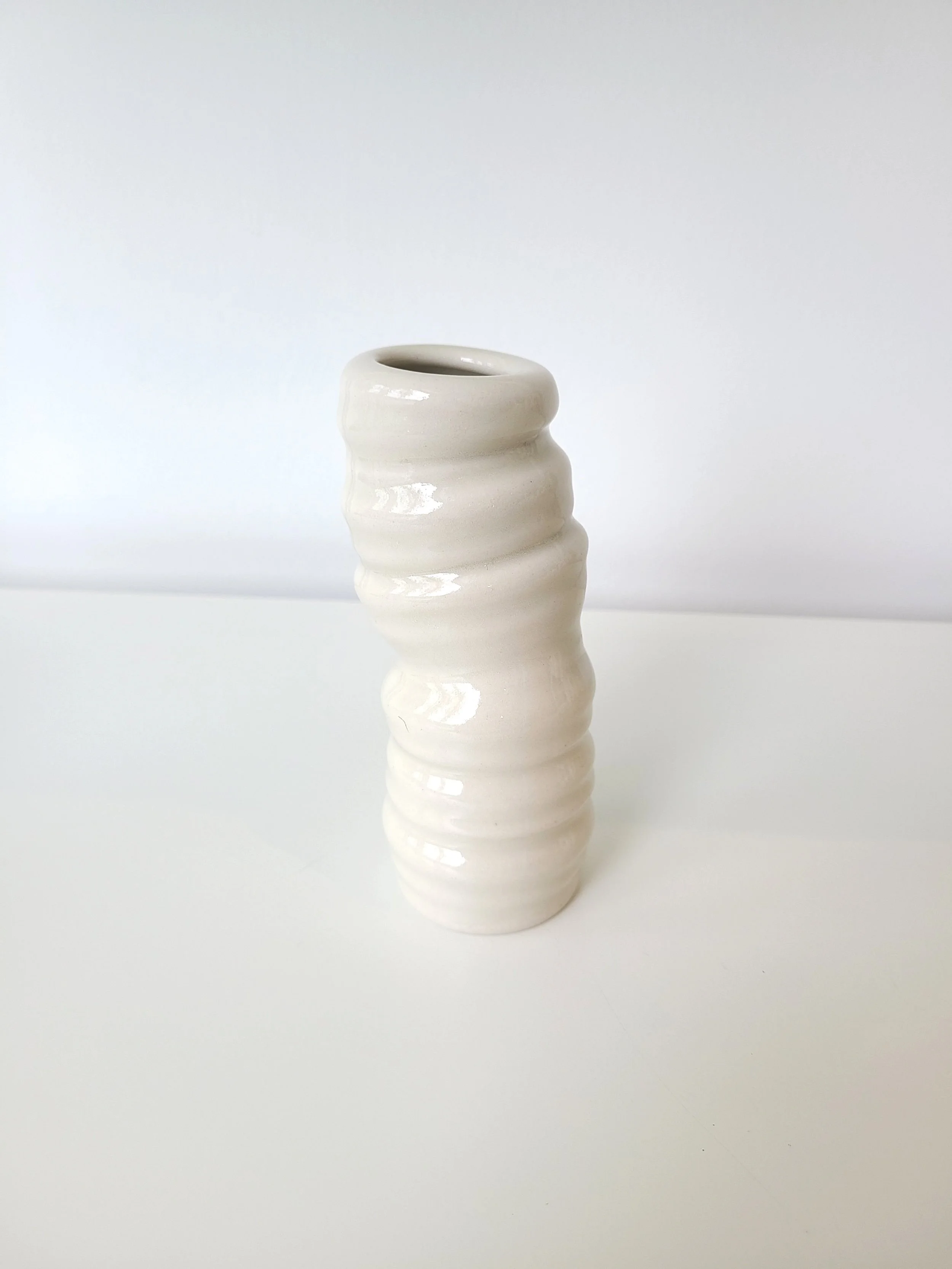 White ceramic wavy vase against a light gray background.