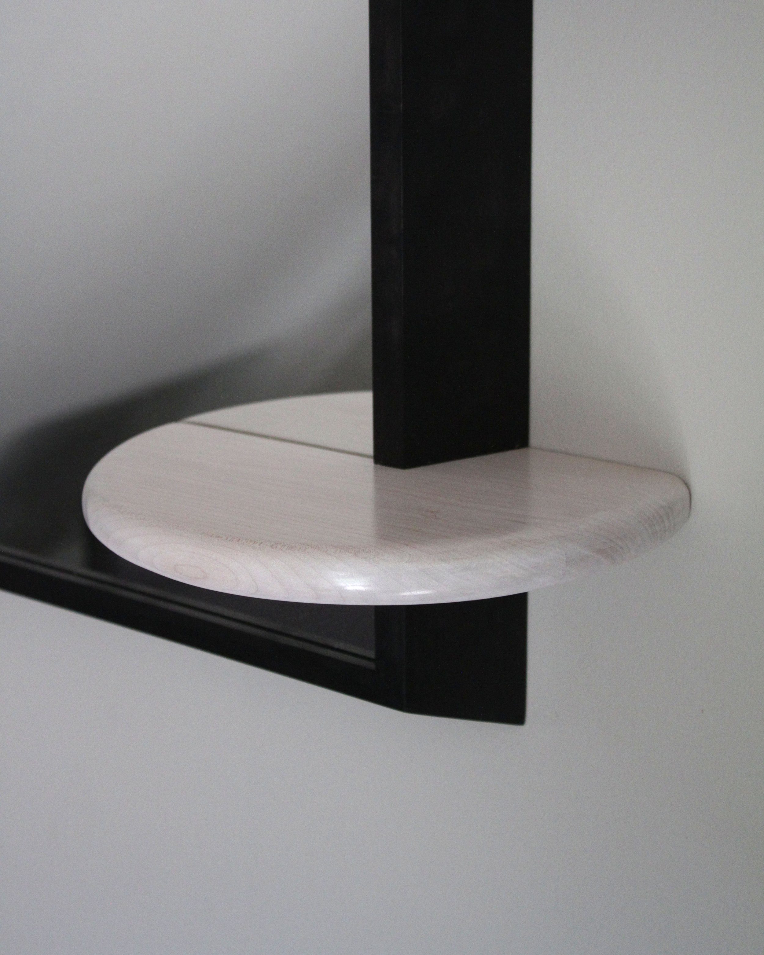 Close-up of a black rectangular object with a dark blurred background, sitting on a white circular base.