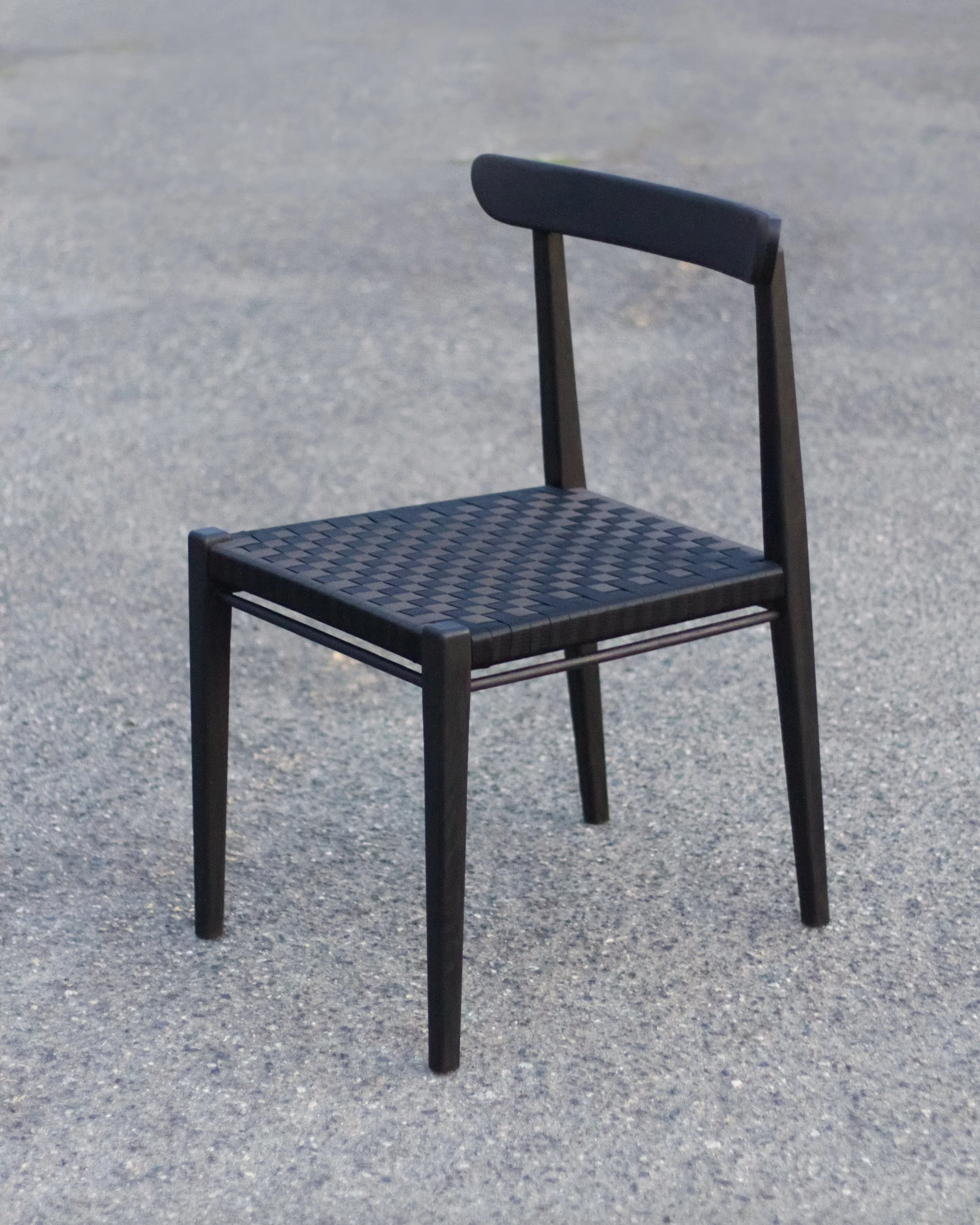 A modern black oak chair with a woven seat.