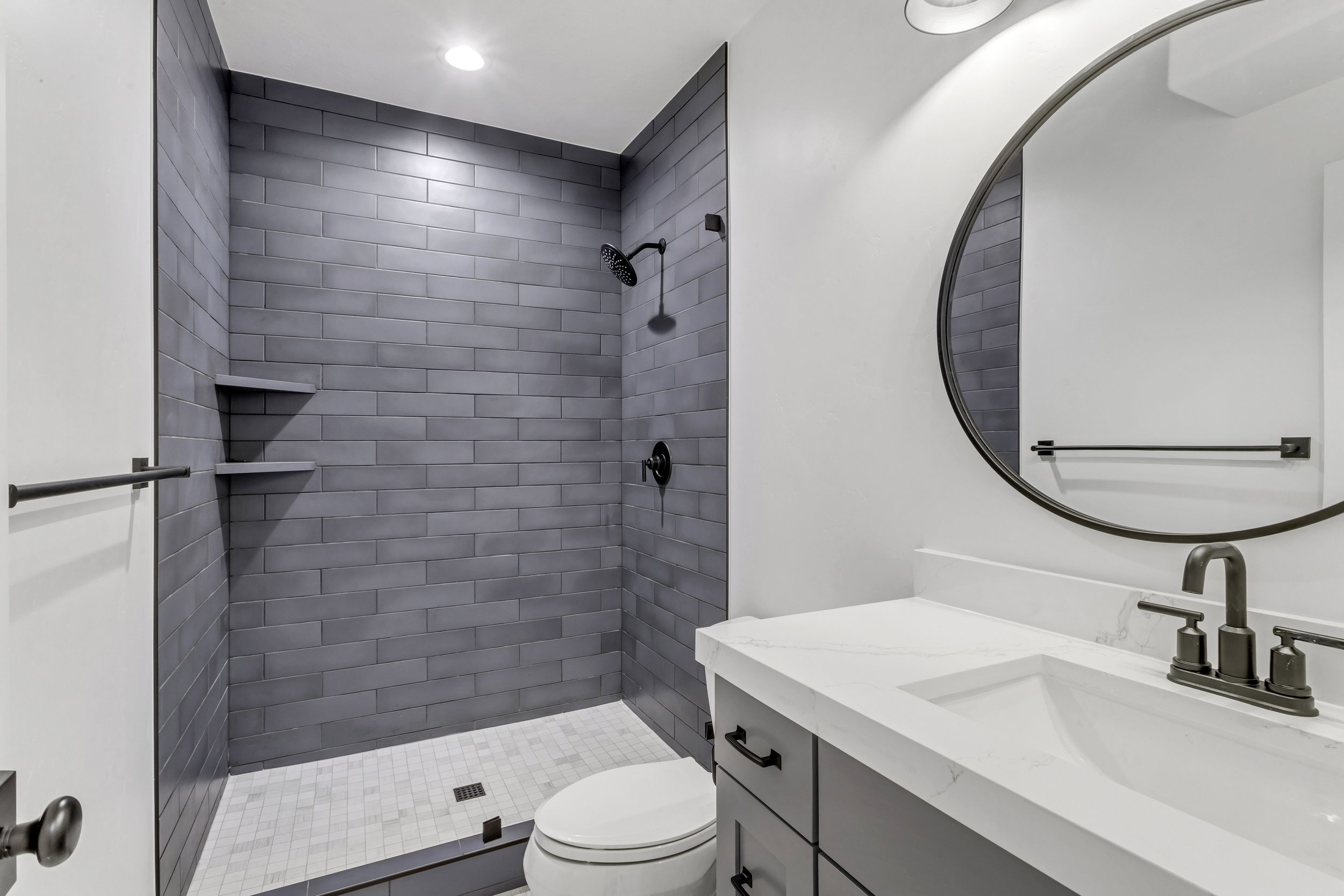 Basement finish with a modern bathroom featuring a walk-in tile shower, custom vanity, and black fixtures in Tooele Utah