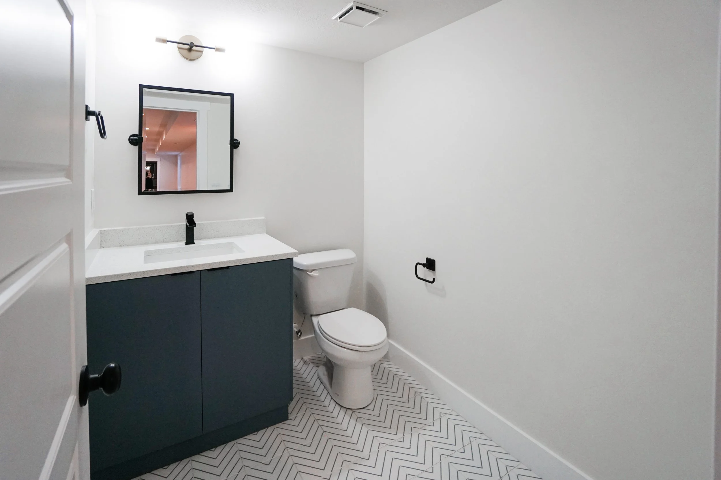 Basement finish with modern bathroom vanity, chevron tile flooring, updated lighting, and sleek black fixtures in Stansbury Park