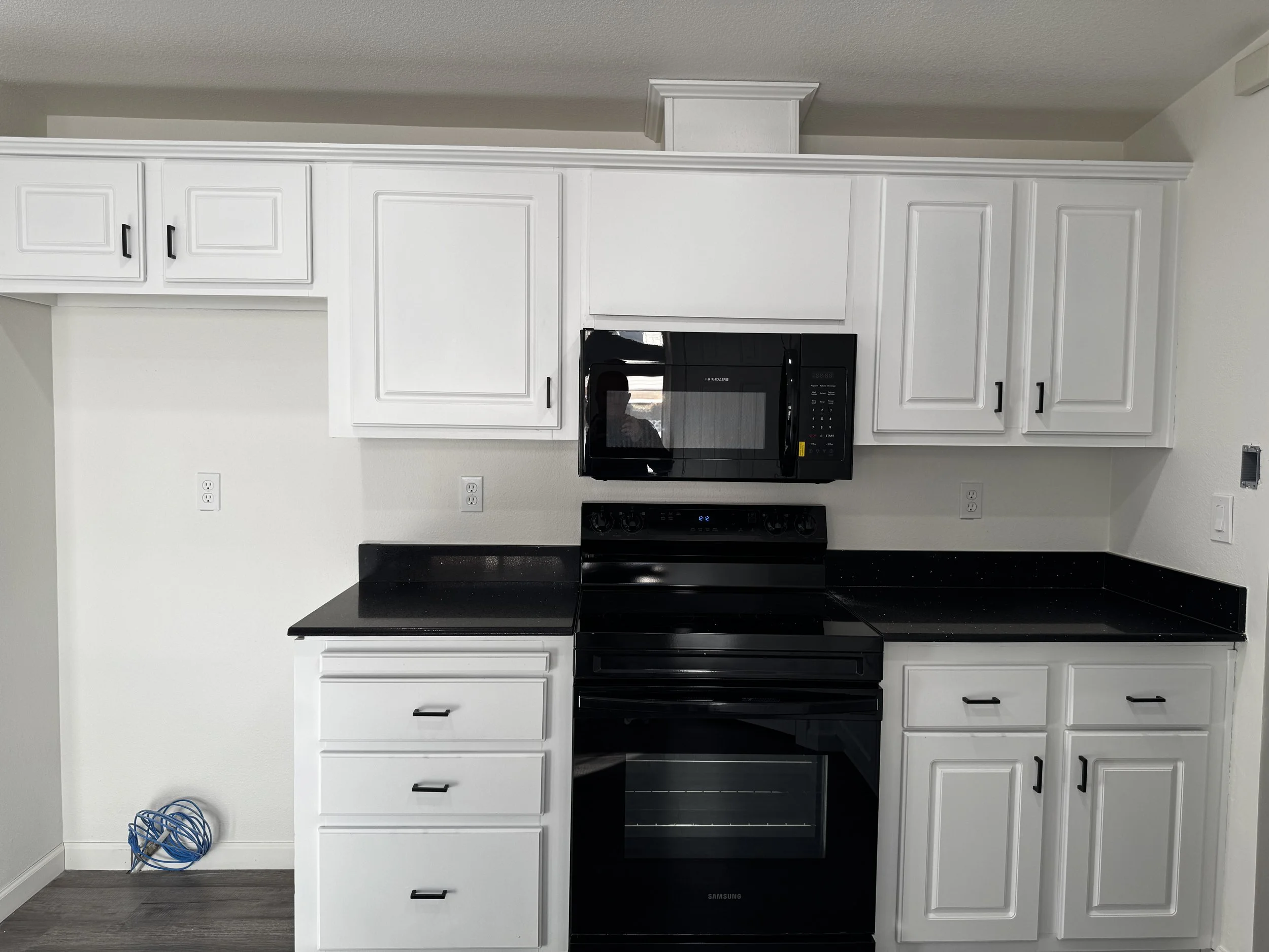 Basement finish with white kitchen cabinets, black appliances, and modern finishes designed for style and functionality in Tooele Utah