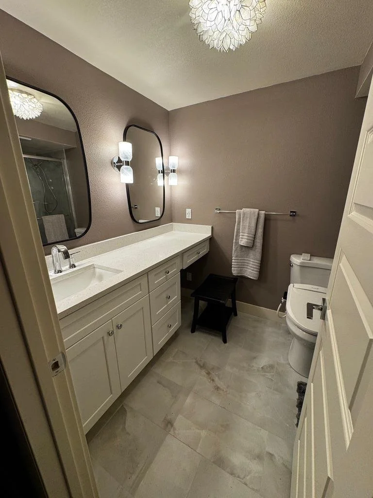 Modern bathroom remodel with double mirrors, white vanity, updated lighting, and tile flooring — proudly serving Tooele County, Stansbury Park, Grantsville, Erda, Stockton, and nearby Utah areas.