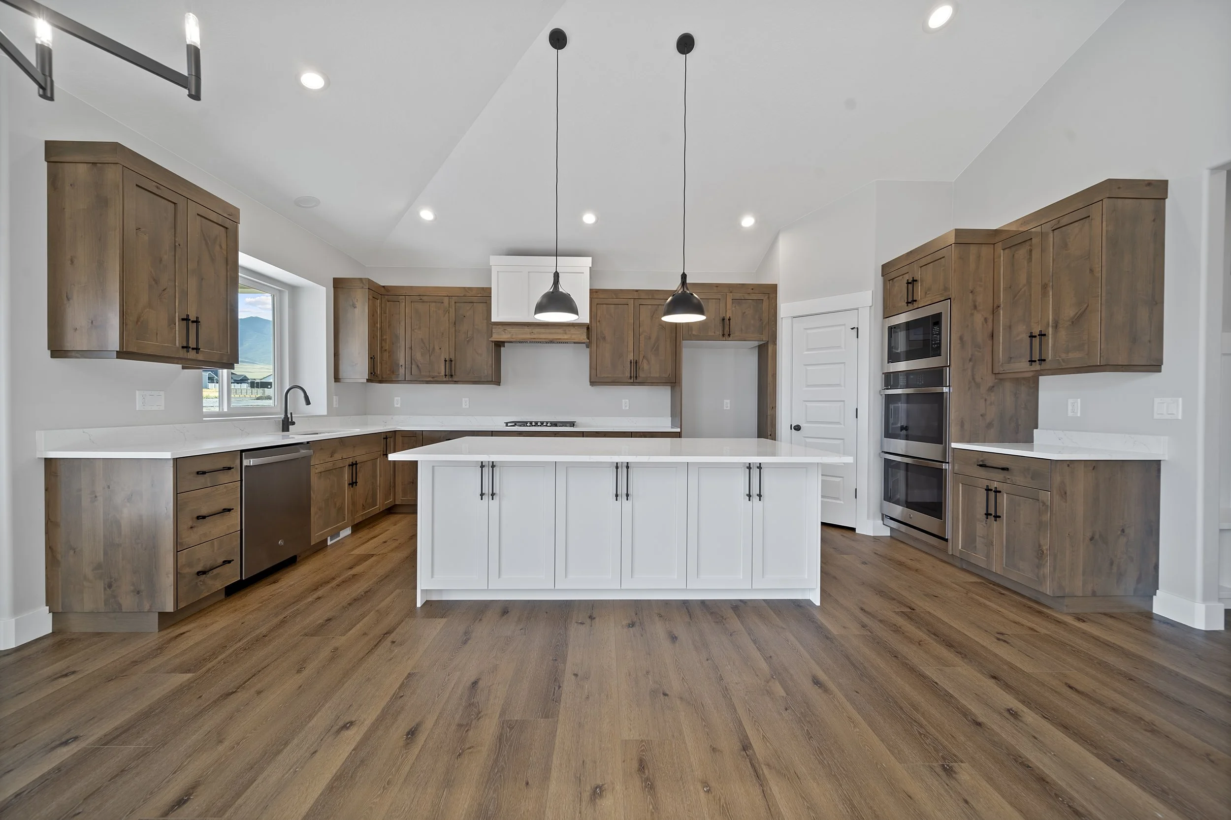 Modern kitchen with wood cabinets, white island, stainless steel appliances, and hardwood flooring.