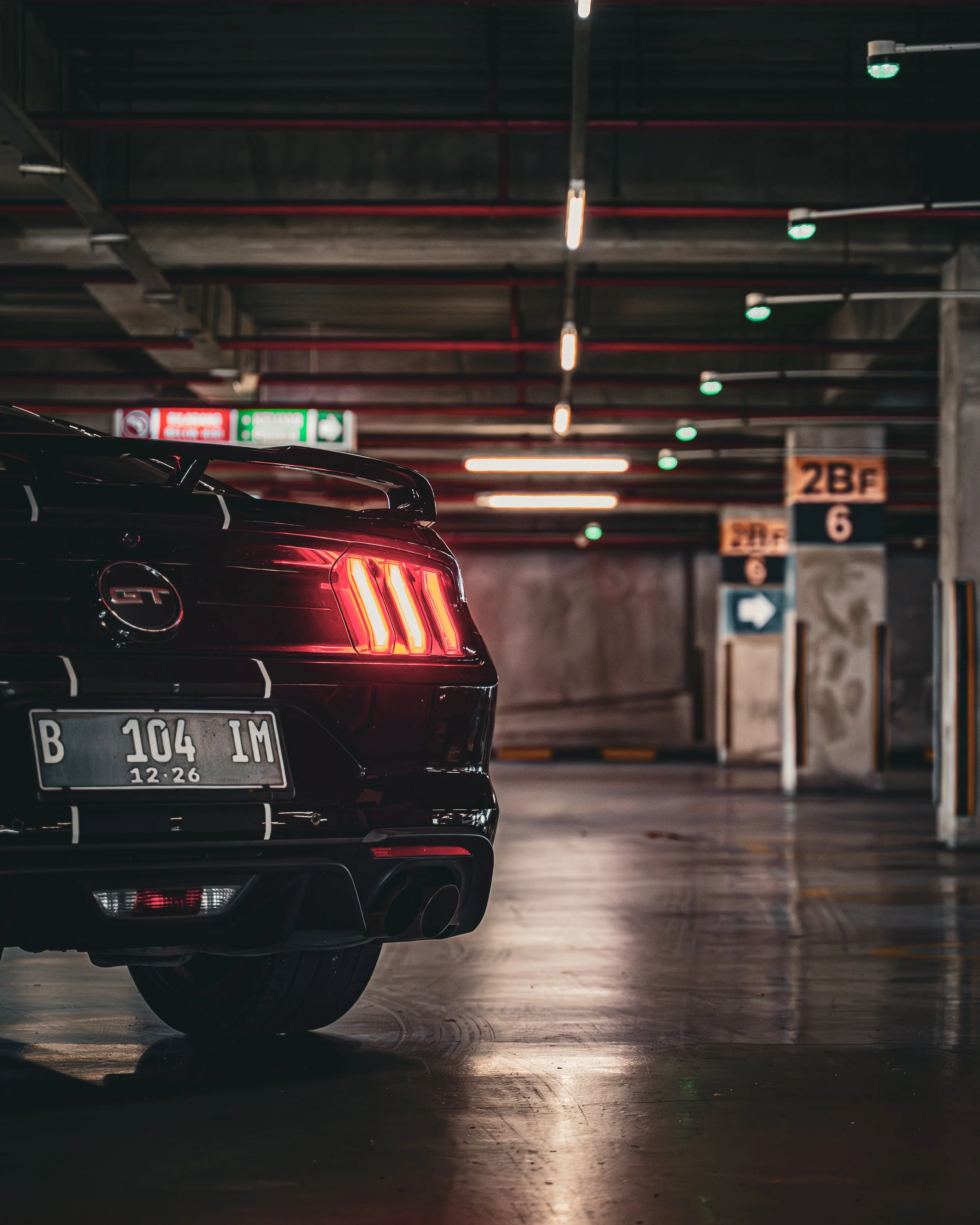 Rear view of a black Ford Mustang GT in a dimly lit indoor parking garage.