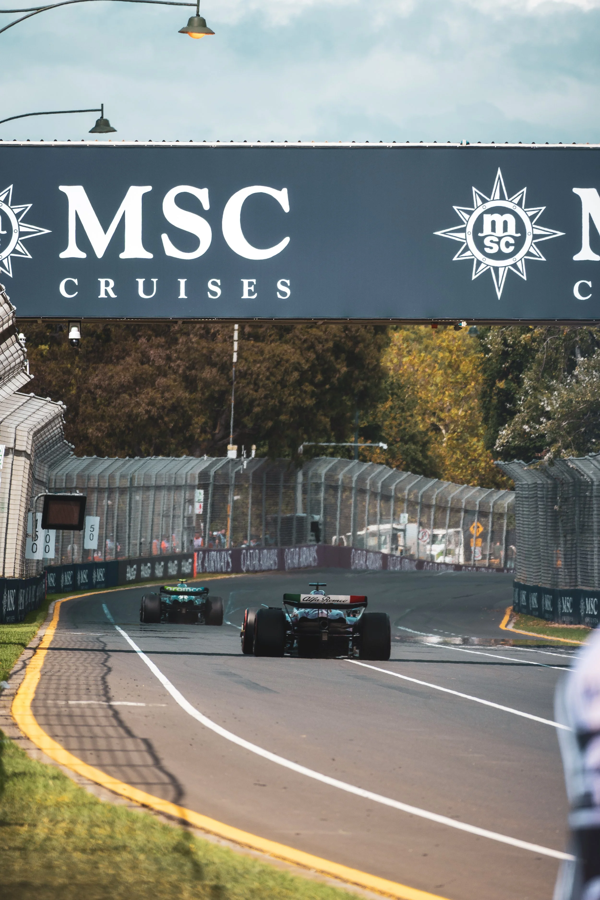 Race cars speeding on a track beneath a large MSC Cruises banner at a motorsport event.