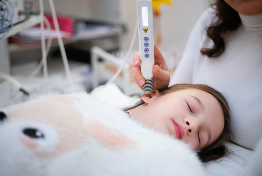 Ärztin führt Ultraschalluntersuchung bei einem schlafenden Mädchen im Krankenhaus durch.