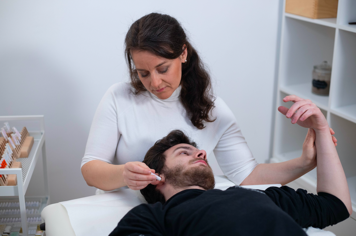 Eine Frau führt einem Mann eine medizinische Untersuchung während einer Behandlung oder eines Tests durch, in einem Behandlungsraum.
