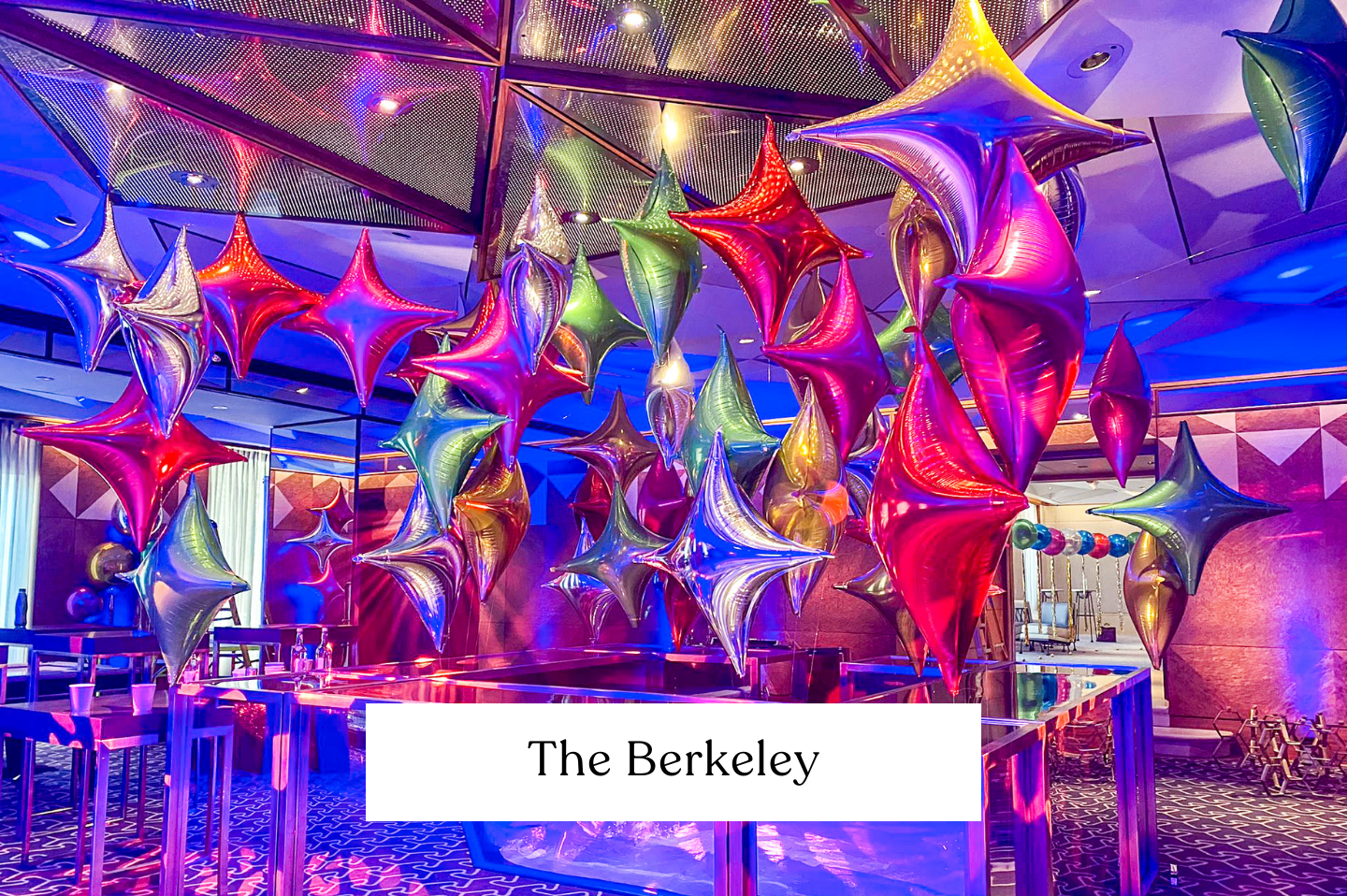 Colourful balloon art star point foil installation with star-shaped balloons in pink, silver, green, purple, and gold, in a decorated indoor space with reflective surfaces and patterned carpeting, at The Berkeley.