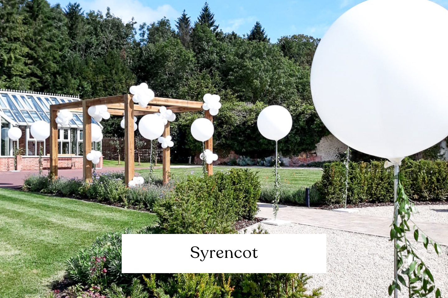 Outdoor garden decorated with numerous giant white balloons on base plates, party pillars.