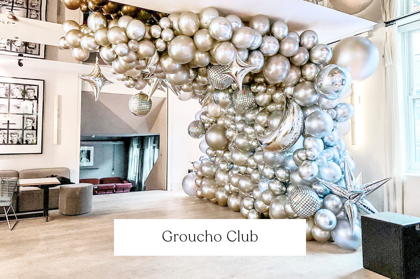 A large indoor space decorated with silver balloons and star-shaped balloons forming a cluster, with some balloons reflecting the room. Groucho Club, London. 