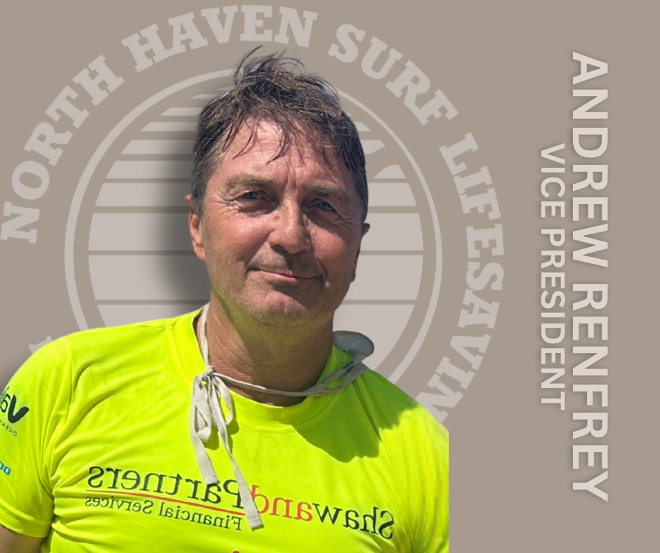 A man wearing a bright yellow t-shirt with a logo and text, standing outdoors in front of a backdrop with a logo and text related to North Haven Surf Life Saving, and the name Andrew Renfrey with the title Vice President.