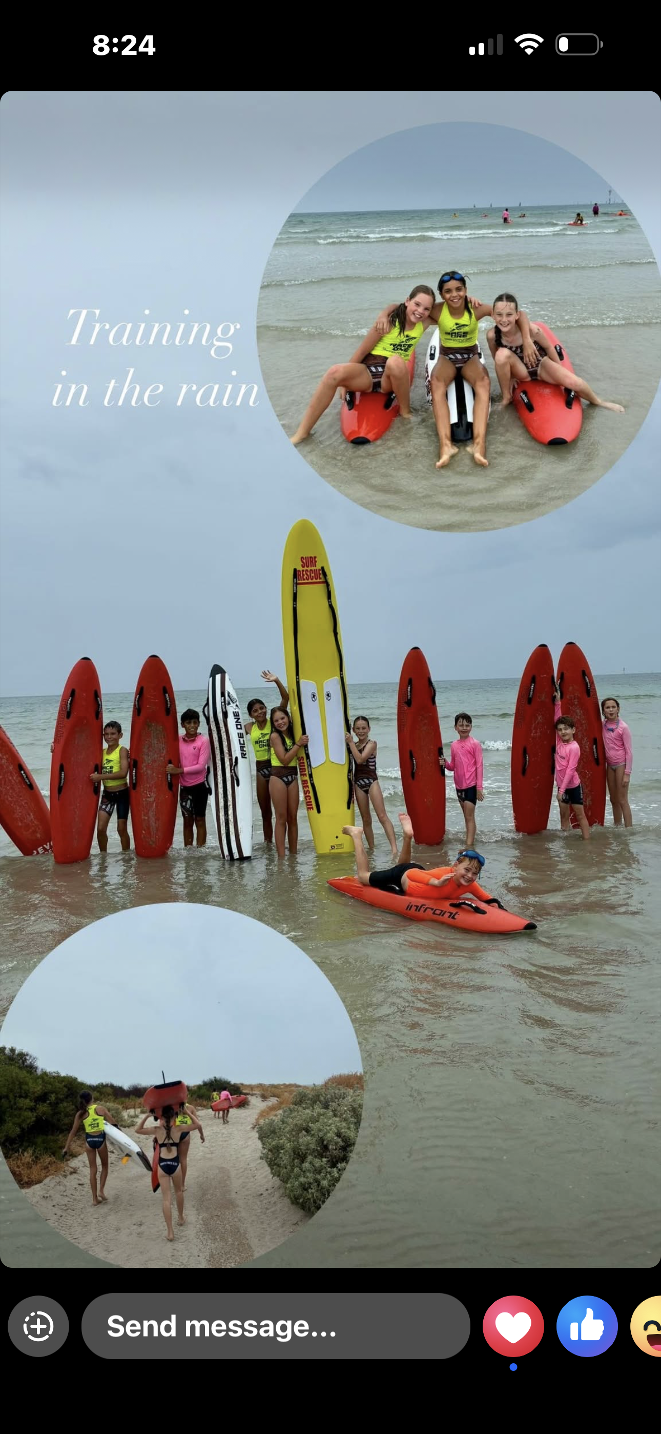 Group of children at the beach with surfboards and paddleboards, some standing in shallow water, others walking on sand carrying equipment, during grey cloudy weather.