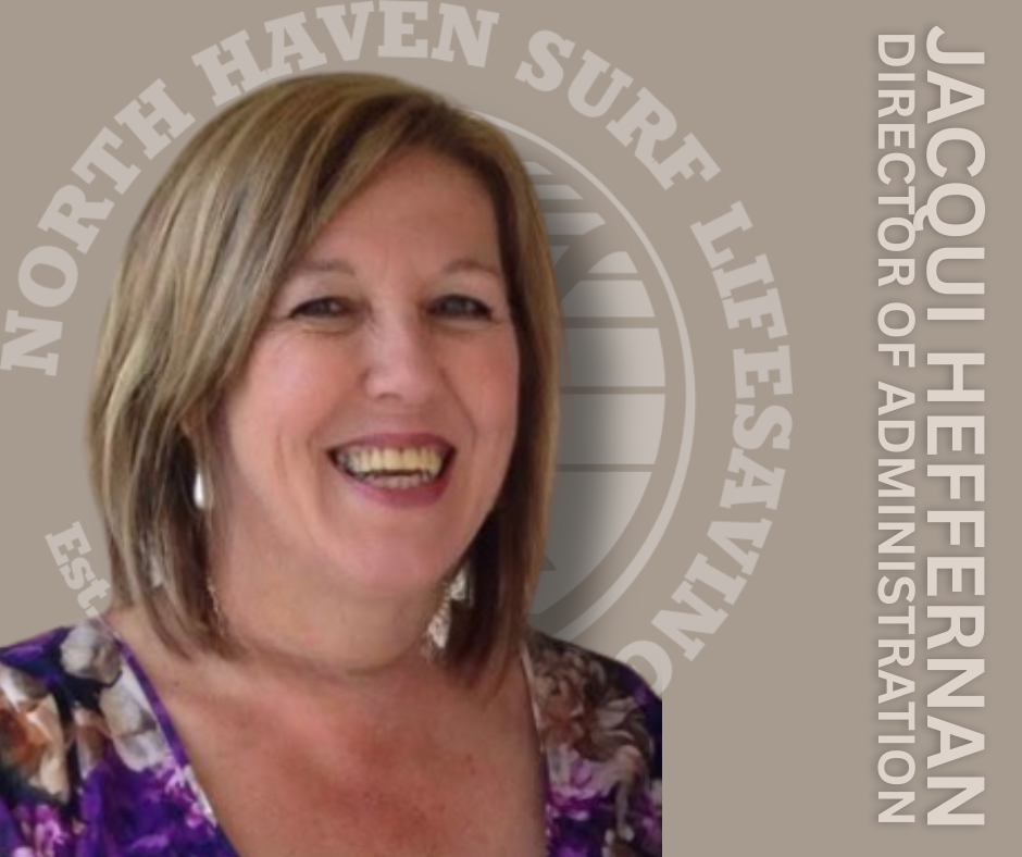 A woman with shoulder-length light brown hair, smiling, wearing a purple floral blouse, standing in front of a background with the logo and text of North Haverbrook Life Safety and Jacqui Hefernan, Director of Administration.