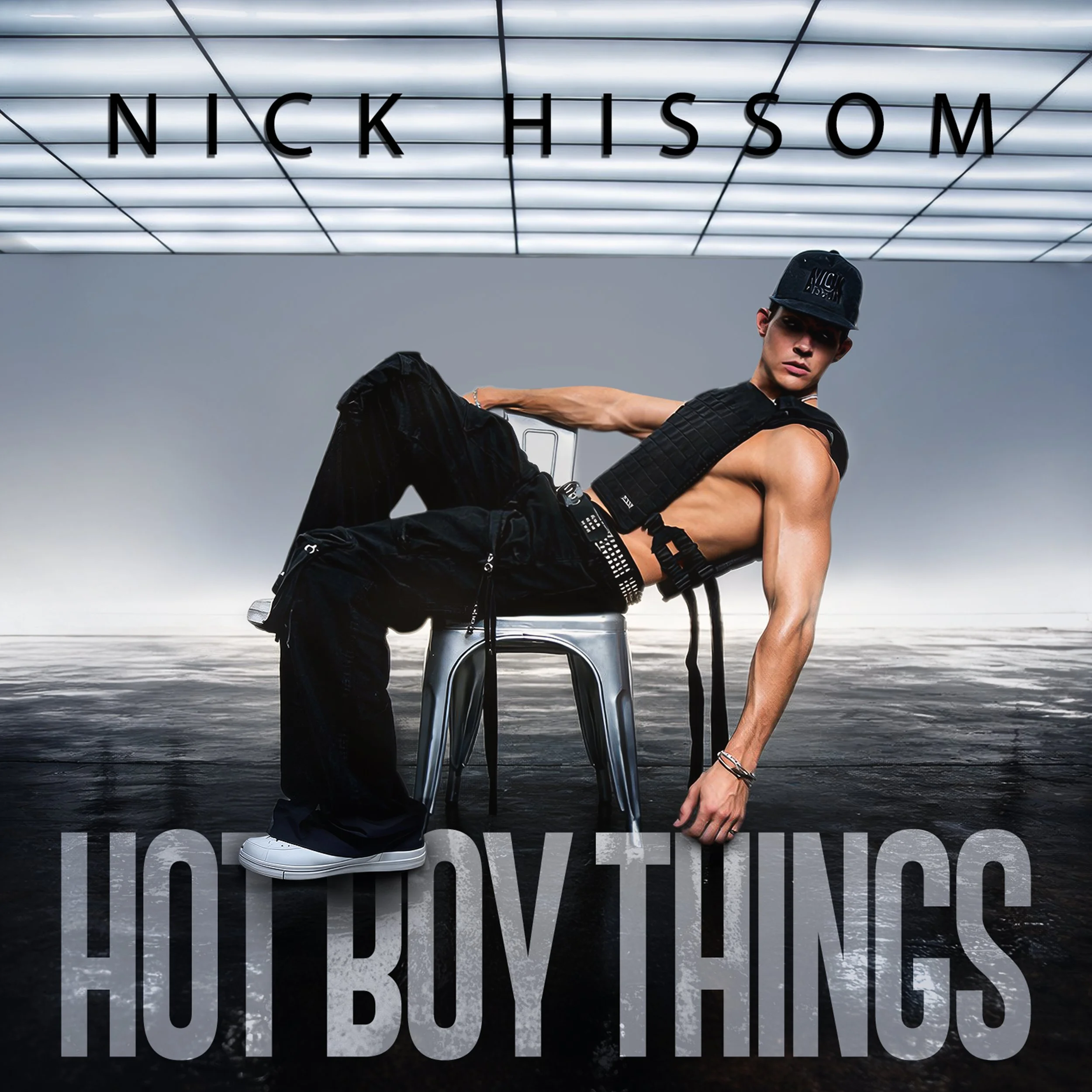 Official single artwork for "Hot Boy Things" by Nick Hissom. Showing the artist reclining in a military vest with muscular arms sitting on a chair set against a cinematic grey background.