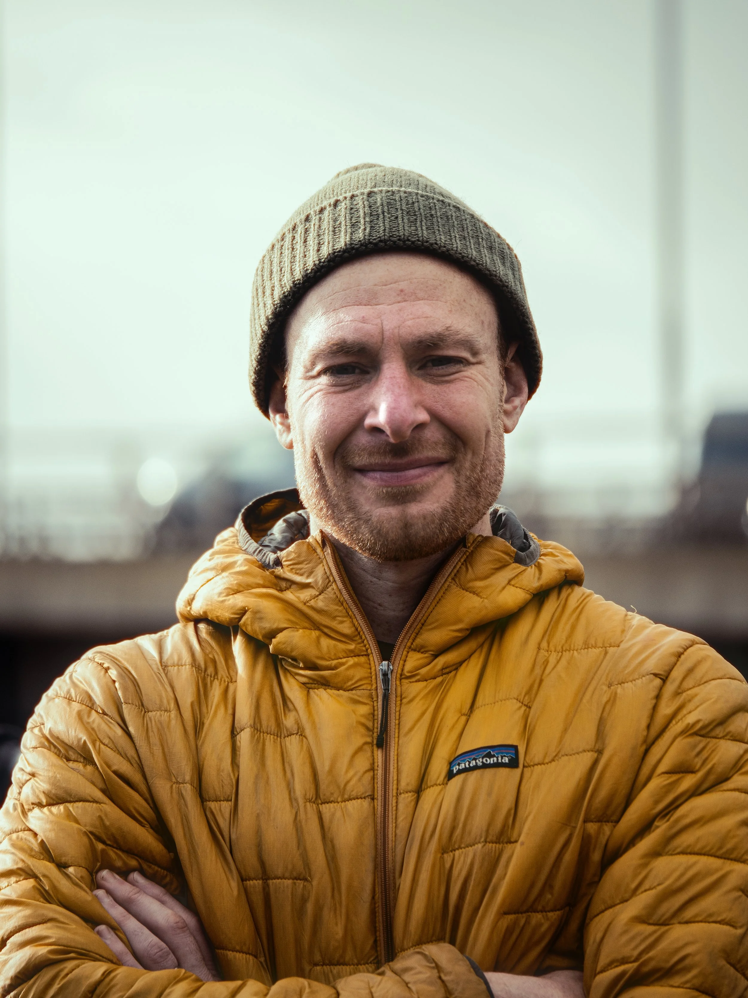 Greig Corr-Macleod, a Glasgow based running coach, wearing a yellow jacket and green hat and looking directly at the camera
