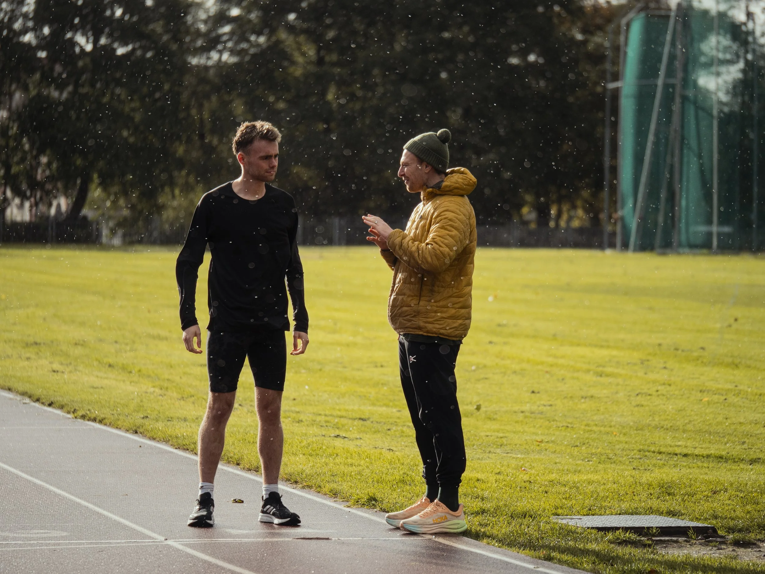 Greig standing on a running track with a client offering run coaching services in Glasgow