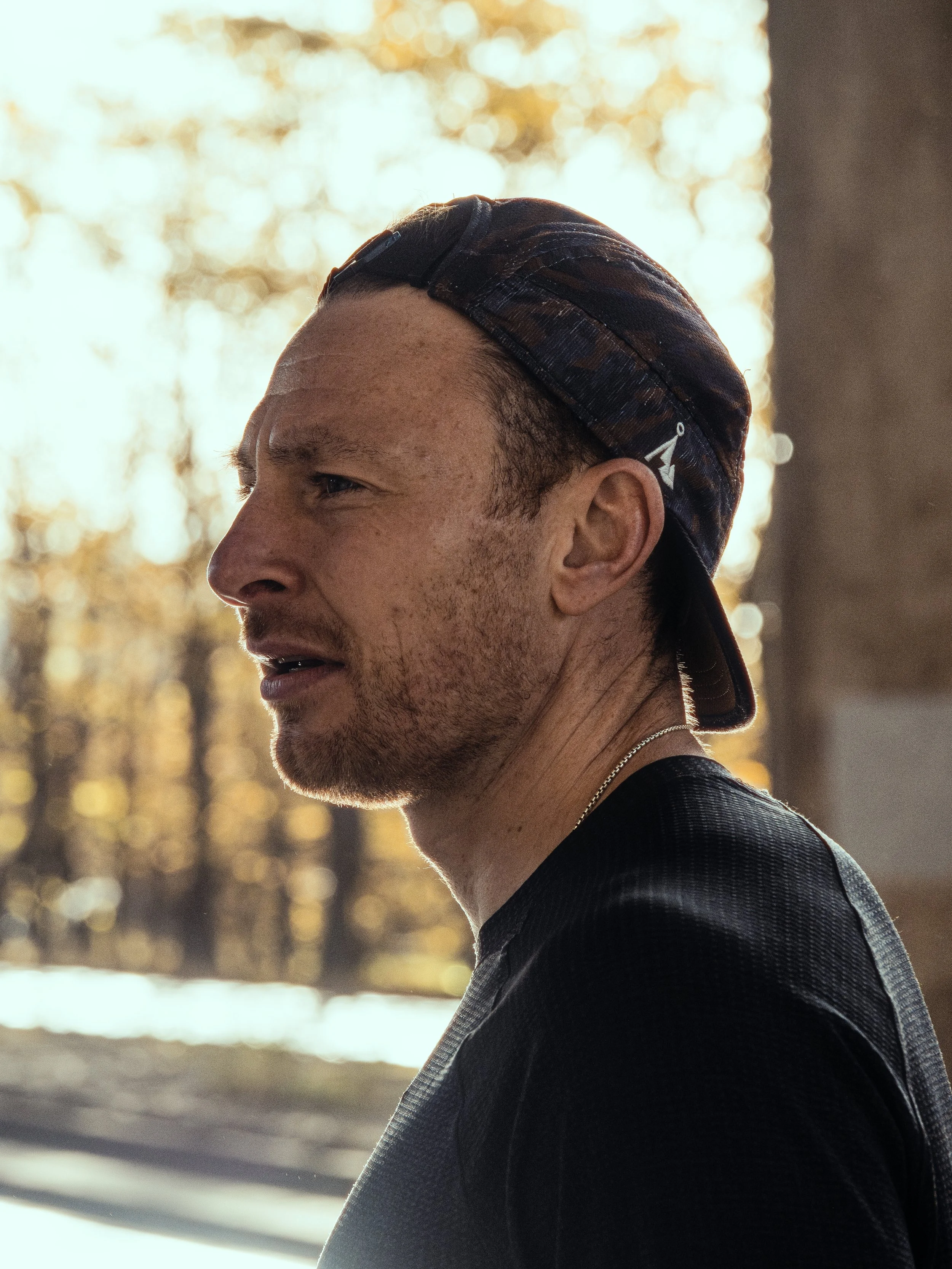 Greig Corr-Macleod, a Glasgow based running coach and personal trainer wearing a black t shirt and cap and staring off to the side