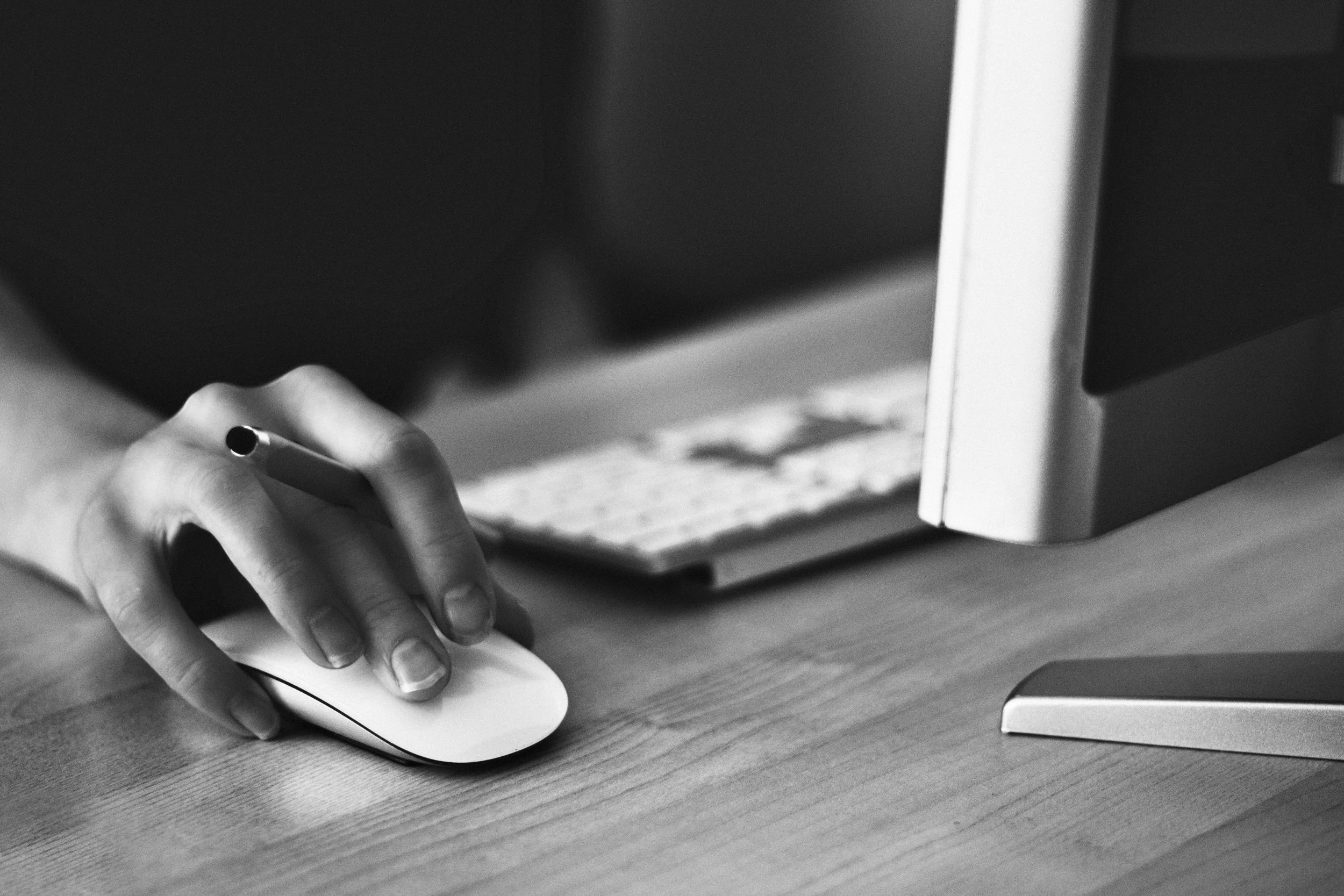 Close-up of a person's hand using a computer mouse at a desk.