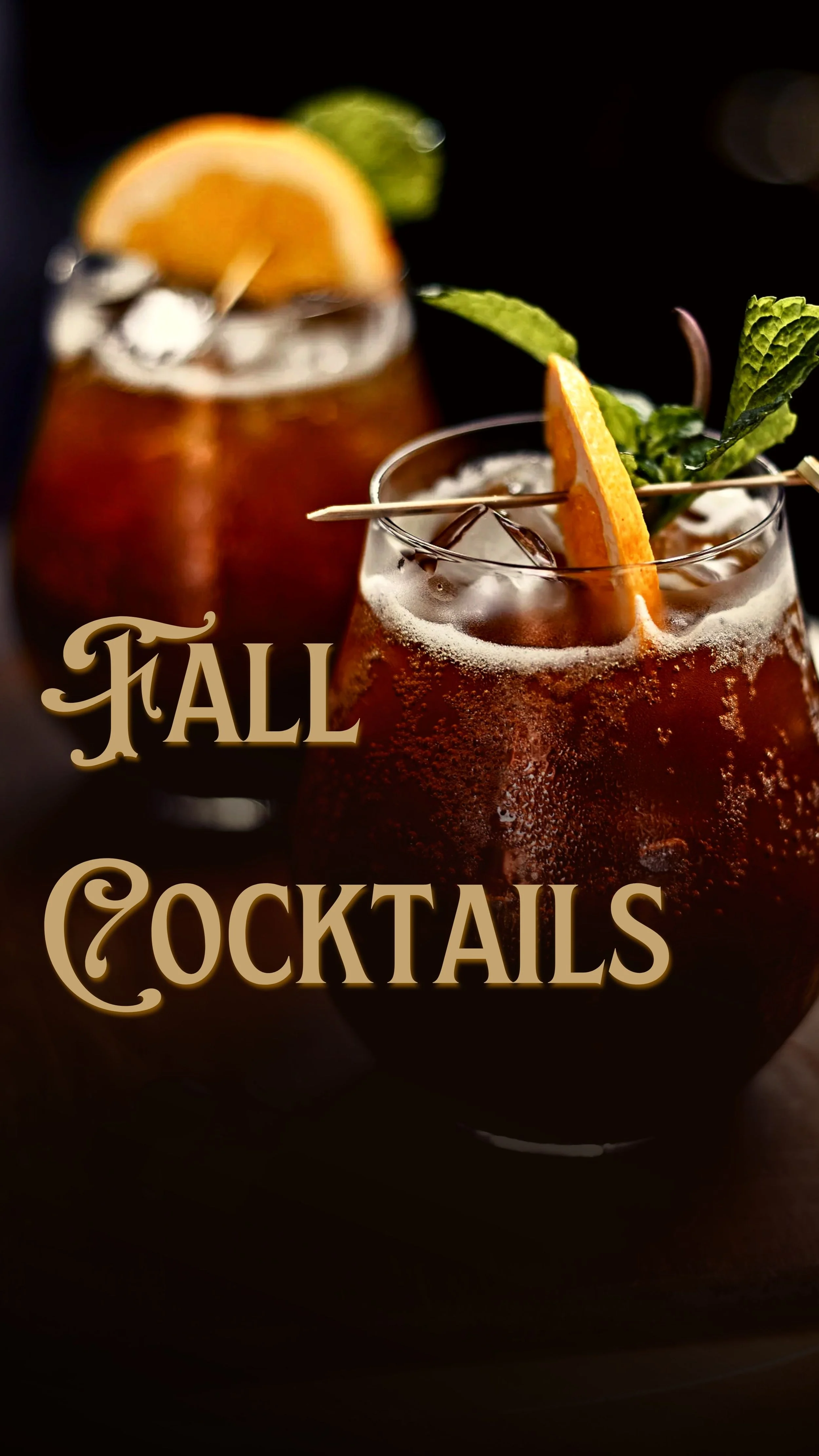 Two glasses of fall cocktails garnished with orange slices, mint leaves, and skewered with wooden picks against a dark background.