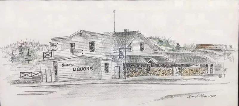 A detailed pencil sketch of a Liquor store named Aurora Liquors, featuring a two-story building with signage, a small outdoor area with a railing, and a stone wall at the storefront, with trees in the background and a signature at the bottom right.