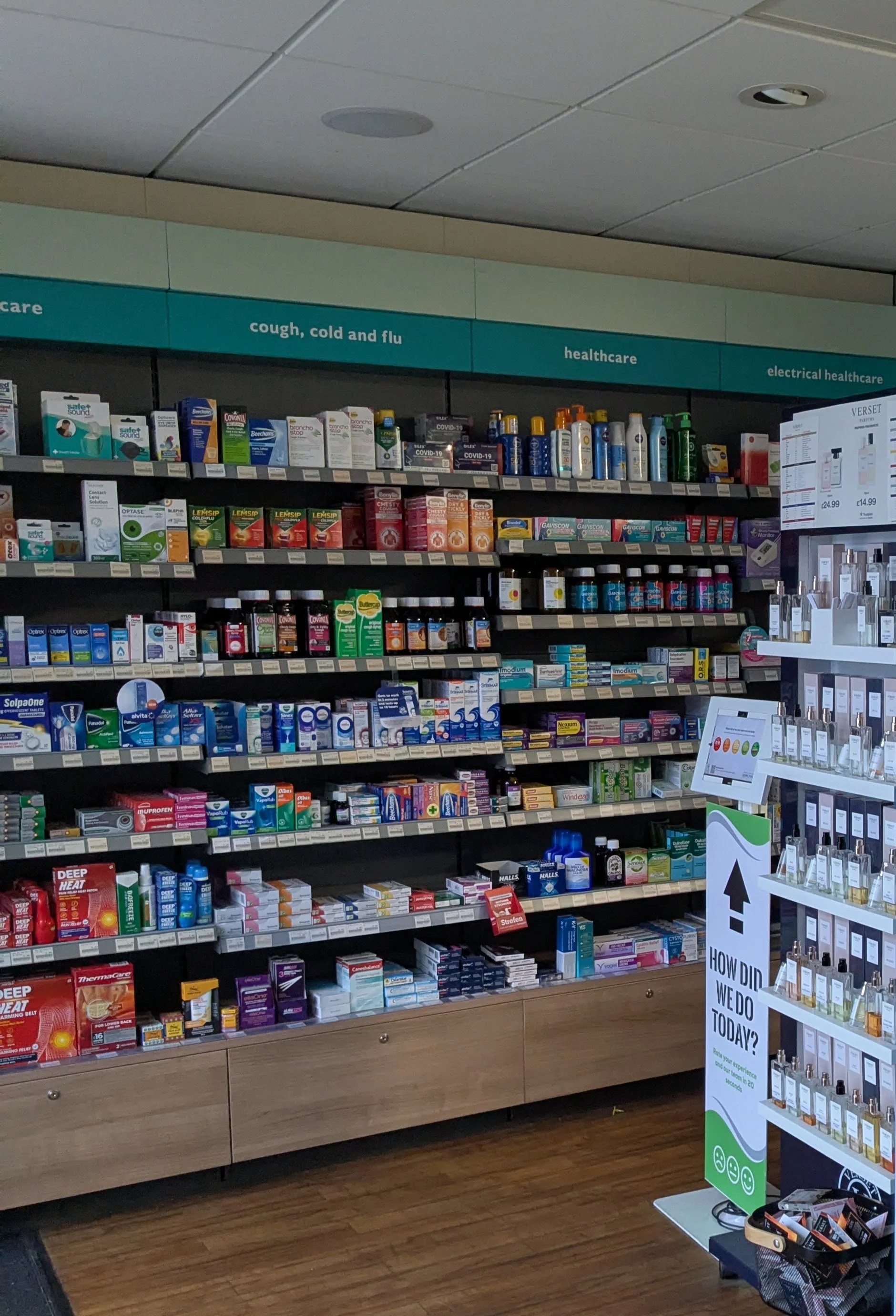 A pharmacy or retail store shelf stocked with over-the-counter medications and healthcare products, categorized under cough, cold and flu, healthcare, and electrical healthcare sections.
