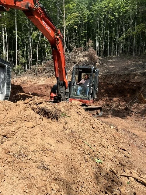 Land clearing for building site with excavation of new septic tanks and main drain lines.