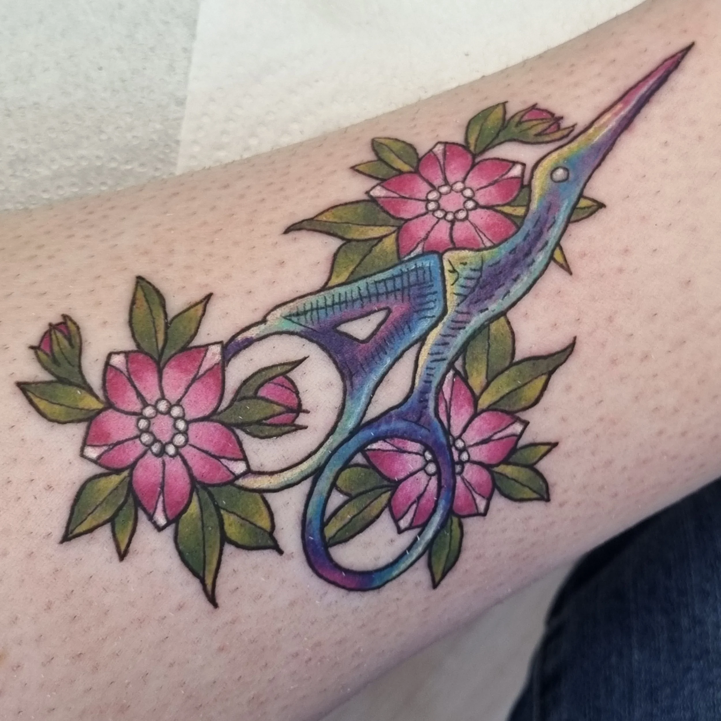 A colour neo-traditional style tattoo of a pair of embroidery scissors and flowers
