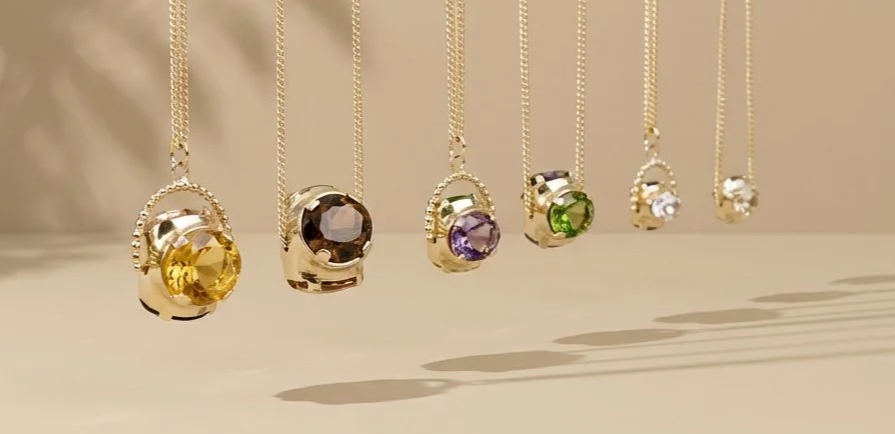 Woman with long blonde hair, wearing a sleeveless top and beige pants, conducting a spiritual or healing ritual with a large crystal sound bowl with a person lying on a massage table, in a room with wooden walls and decorative sculpture.