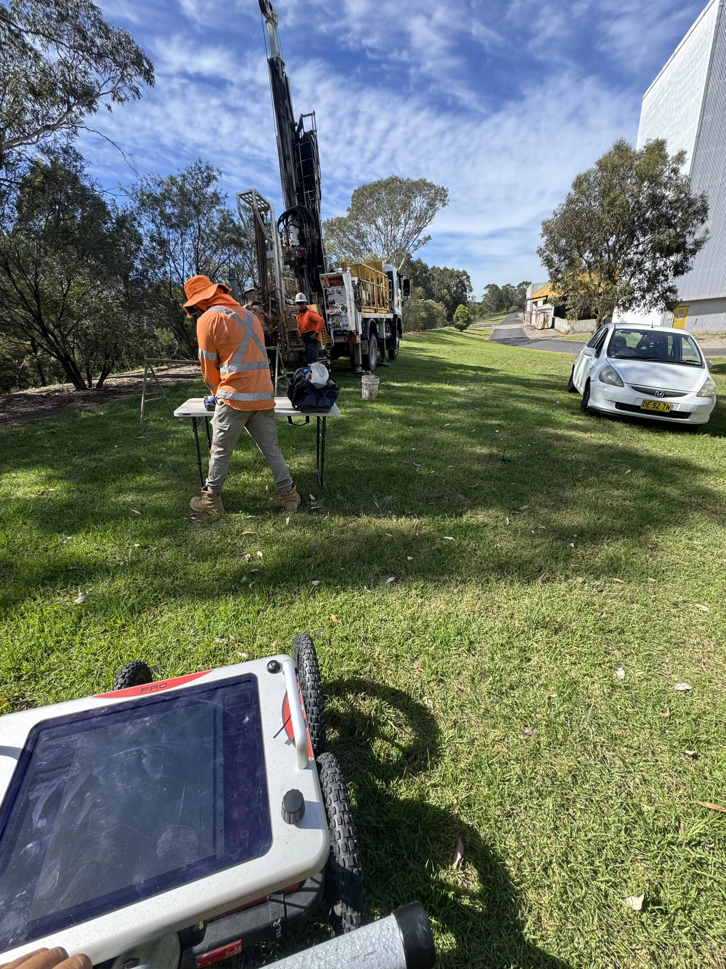 A person conducting outdoor geological survey with a metal detector near a utility pole.