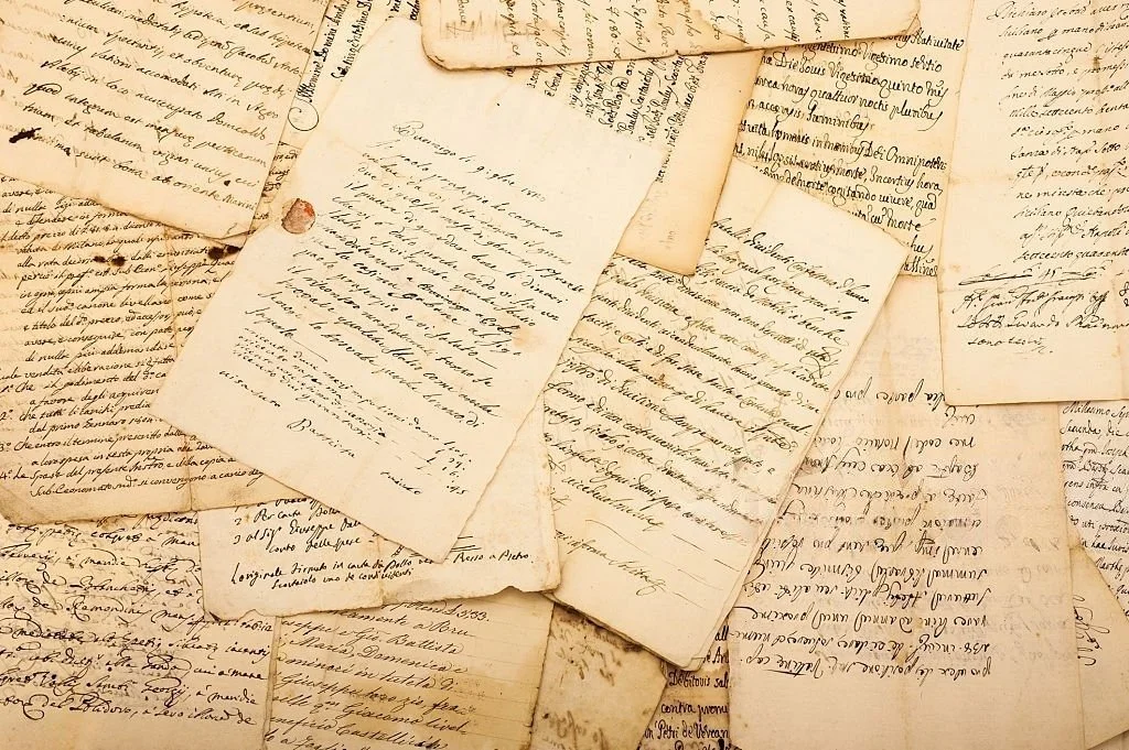 Collection of old handwritten letters and documents in various sizes and orientations with aging paper and cursive script.