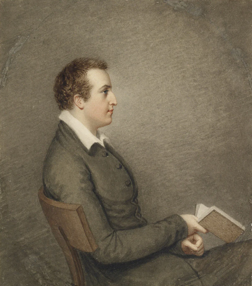 A realistic painting of a young man with short, curly hair, wearing a gray blazer and white shirt, sitting on a wooden chair, holding an open book in his left hand, and looking to the left against a plain, muted background.