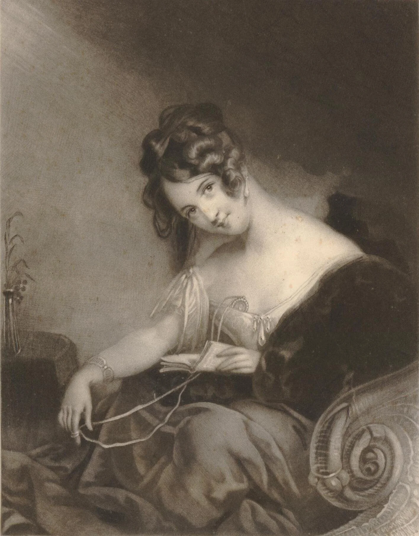 A black and white portrait of a woman sitting in a relaxed pose, holding a book in her left hand and a string in her right hand. She has curly hair arranged in an updo and is wearing a dark dress with an off-the-shoulder neckline. The background is plain with a subtle shadowed gradient.