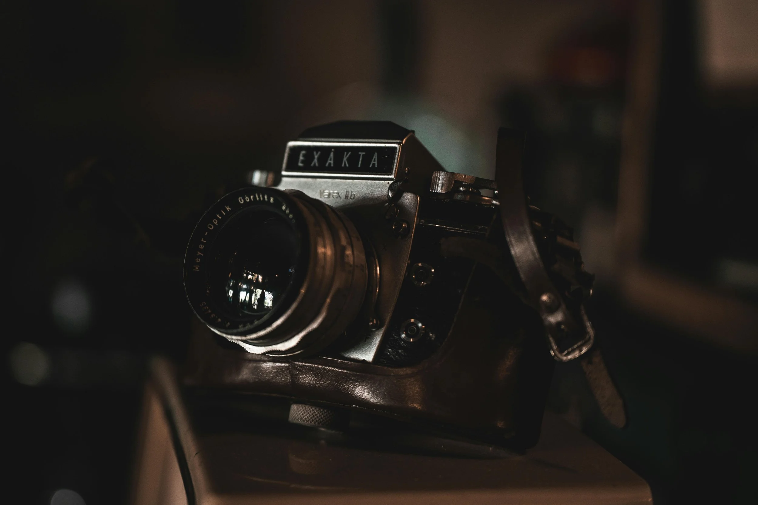 Close-up of a vintage Exakta camera with a Meyer-Optik Görlitz lens, placed on a dark surface with a blurred background.
