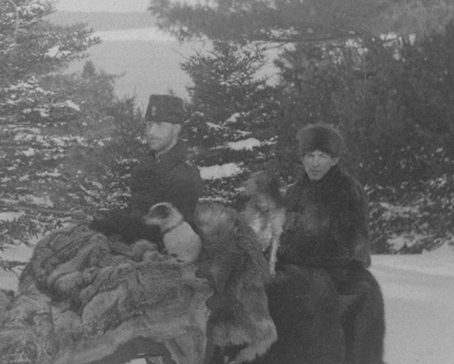 Close-up detail, from an archival photograph, of two officers of the British Army's Corps of Royal Engineers going for an intimate winter sleigh ride together in the snowy wilderness of Point Pleasant Park at Halifax, Nova Scotia in 1870, with dogs.
