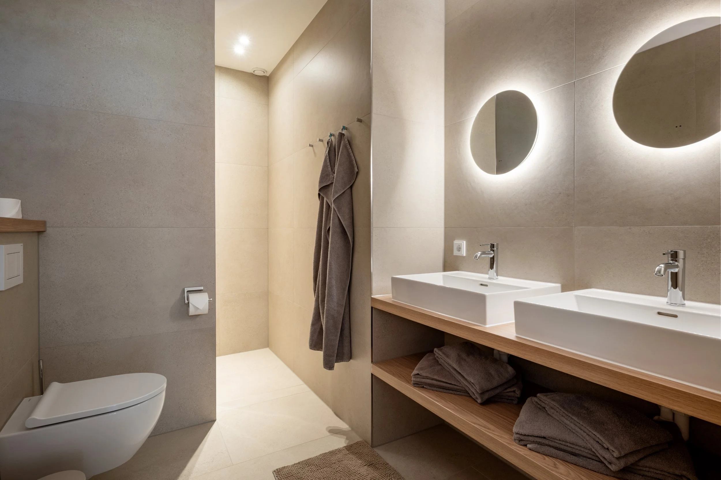 Modernes Badezimmer mit Dusche, WC, zwei Waschbecken mit Spiegel, Föhn, Handtücher 
