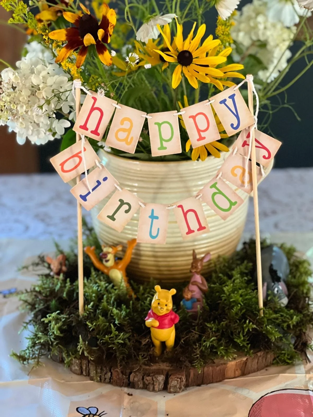 A flower pot with a "Happy Birthday" sign and characters from Winnie the Pooh for a birthday celebration Anne Plan ned.