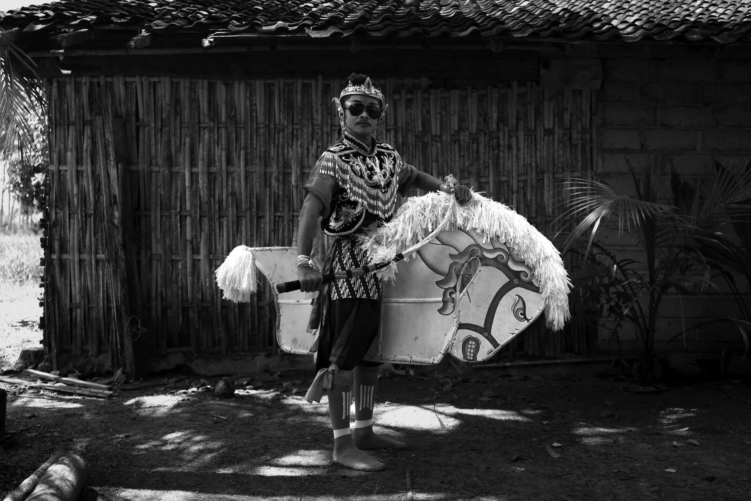 Jaranan performer posing in front of a bamboo fence.