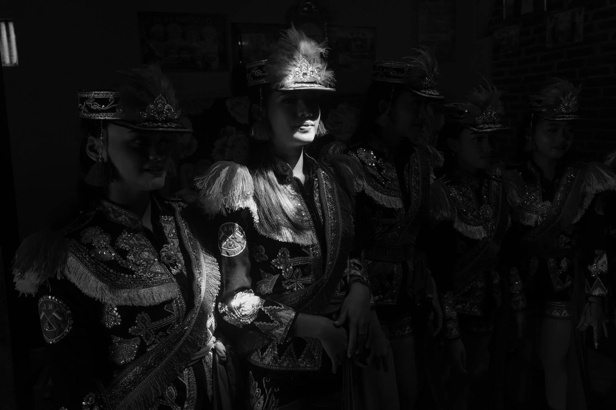 Group of female dancers dressed in traditional ndolalak costumes with ornate embroidery and feathers, wearing hats with feathers, standing in a row in Purworejo, Central Java