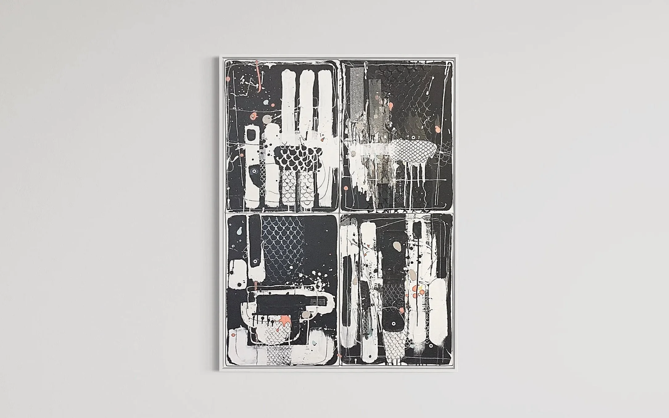Abstract mixed media art piece with black, white, beige, and red paint splatters and patterns in a white frame, hung on a plain white gallery wall.