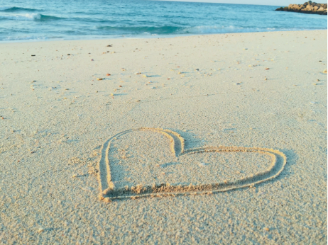A heart drawn into the sand on a sandy beach