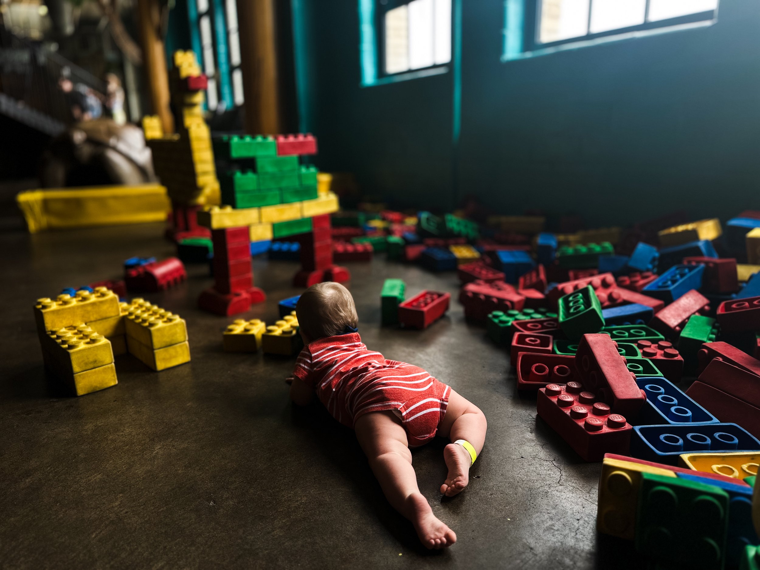 moody portrait of boy in red and white outfit lays surrounded by colored blocks in children's museum, clarksville tn, nashville tn, photographer, documentary, lifestyle, family photographer